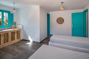 a bedroom with green doors and a bed and a sink at Nissia Beach Apartments & Suites in Kamari