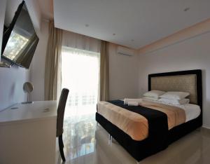 a bedroom with a bed and a desk and a television at Athena Apartment in Artemida
