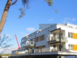 ein weißes Gebäude mit Balkonen und einem Baum in der Unterkunft Ferienwohnung Traumsegler in Juliusruh