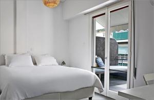 a white bedroom with a white bed and a sliding glass door at Acropolis charming apt with large balcony - DM17 in Athens