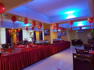 un salón de banquetes con mesas rojas y globos en Royal Gardens Hotel, en Sohar