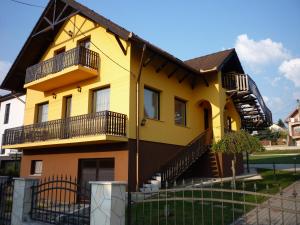 ein gelbes Haus mit schwarzem Dach in der Unterkunft Apartmanház King in Hévíz