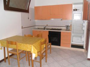 マルティンシクーロにあるAppartamento Capriのキッチン(テーブル、椅子、冷蔵庫付)