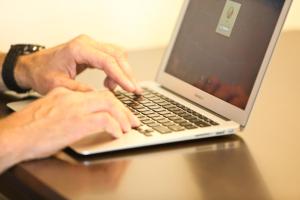 een man die typt op een laptop computer op een tafel bij AmericInn by Wyndham Winona in Winona