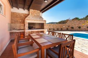 a patio with a wooden table and a fireplace at Villa Roza Murter in Murter