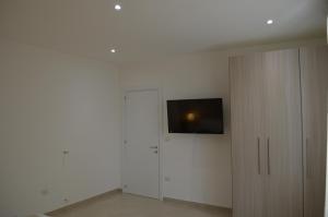 Habitación blanca con TV y armario blanco en Casa Low Cost, en Tuglie