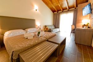 a bedroom with a large bed with a bench in it at Villa Carolina Resort in Castelletto d'Orba +51 photos