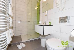 a white bathroom with a toilet and a sink at Hotel Am Kurpark in Brilon