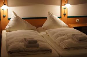 ein Bett mit zwei Handtüchern und zwei Kissen darauf in der Unterkunft Landgasthof Hoffnung in Handewitt