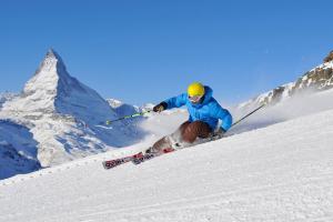 Ein Mann fährt einen schneebedeckten Berg hinunter in der Unterkunft Typically Swiss Hotel Täscherhof in Täsch