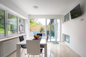 a dining room with a table and chairs and windows at Apartment Jasna in Zagreb