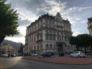 ein großes Gebäude mit davor geparkt in der Unterkunft Suite Grand Hotel Palace Aix les Bains French Alps in Aix-les-Bains