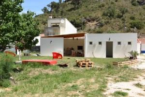 una pequeña casa blanca con una silla roja y una mesa en Horta do Vale - Nature House en Odeceixe