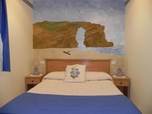 a bedroom with a bed with a painting on the wall at O Lar de Carmiña in Devesa