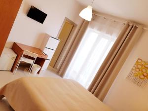 um quarto com uma cama, uma janela e uma secretária em B&B Mimosa em Giardini Naxos