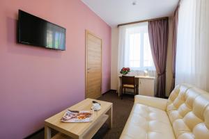 a living room with a couch and a tv on a pink wall at Hotel Galereya in Tomsk