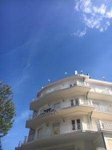 a tall white building with a blue sky in the background at Residence Auriga in Rimini