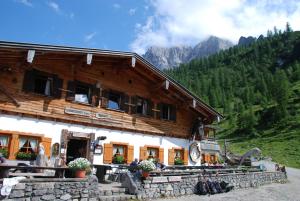 a large wooden building with mountains in the background at Binsalm- Schutzhütte in Vomp