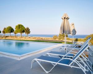 una piscina con due sedie a sdraio e un ombrellone di Luxury Villa Trapezia a Afantou