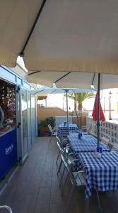 une terrasse avec 2 tables, des chaises et un parasol dans l'établissement Hostal Cubelles, à Cubelles