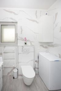 a white bathroom with a toilet and a sink at Villa Apartments Art in Trogir