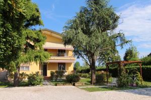 a yellow house with a tree and a gazebo at Appartamenti Giardino al Mare in Cavallino-Treporti