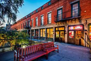 een rode bank voor een bakstenen gebouw bij River Street Inn in Savannah