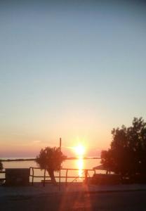 a sunset over a body of water with a fence at Katerina Rooms in Tinos Town