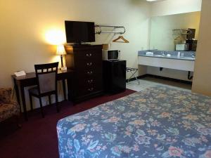 a hotel room with a bed and a desk and a television at Travelers Motel in Cottonwood
