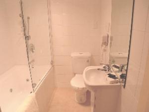 een witte badkamer met een toilet en een wastafel bij ASURE Amalfi Motor Lodge in Christchurch