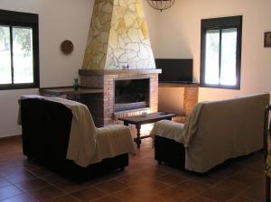 Una sala de estar con dos sillas y una chimenea. en Alojamiento Rural El Chaparral, en Setenil