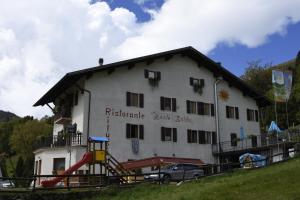 un edificio blanco con un parque infantil delante de él en Rifugio Monte Baldo, en Avio