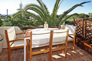 a table and chairs on a patio with palm trees at Villa Angela in Vourvourou