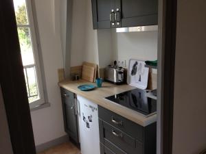 uma pequena cozinha com armários pretos e um fogão em Un petit nid a Honfleur em Honfleur