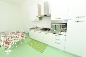 a kitchen with white cabinets and a dining table at Maison Fabrizia in Sorrento