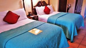 um quarto de hotel com duas camas com lençóis azuis e brancos em The Caribbean Court Boutique Hotel em Vero Beach