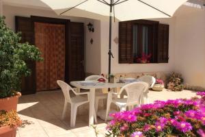 聖維托羅卡波的住宿－Appartamenti Monacò，庭院里配有白色的桌椅和遮阳伞