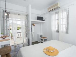 ein weißes Schlafzimmer mit einem Hut auf dem Bett in der Unterkunft Evi Rooms in Aliki