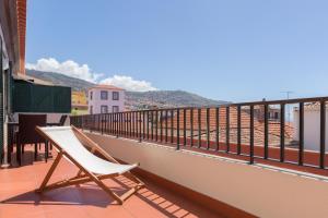 białe krzesło siedzące na balkonie budynku w obiekcie Casa dos Avós by Rent2U, Lda w Funchal