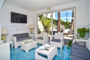 a living room with white furniture and a patio at Charme Hotel La Villa Tina in Ischia