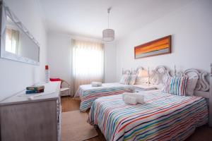 Un dormitorio con dos camas y una mesa y una ventana. en Baleal Beach Holiday Villa, en Baleal