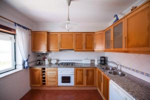 Una cocina con gabinetes de madera y un fregadero. en Baleal Beach Holiday Villa, en Baleal