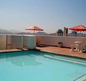 een zwembad op het dak van een gebouw met parasols bij Rivas Apartamentos Santa Marta in Santa Marta