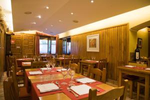 un ristorante con tavoli e sedie in legno e bicchieri da vino di Hostal Rural Salazar a Oronz