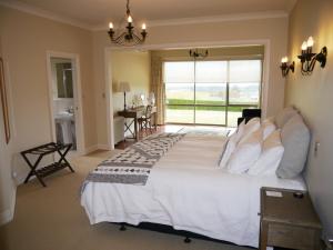 a bedroom with a large white bed with a large window at Country Lodge Kinloch in Taupo