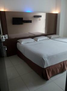 a bedroom with two beds and a tv on the wall at Dream Hotel in Klang