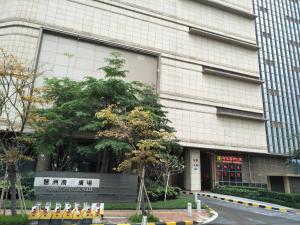 a building with a tree in front of it at Pazhou Angda International Aparthotel Canton Fair Branch in Guangzhou
