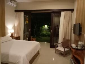 a bedroom with a bed and a window and a television at Guest House Reisya in Nusa Dua