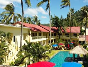 a resort with a swimming pool and palm trees and umbrellas at Austrian Garden Hotel & Restaurant Patong in Patong Beach