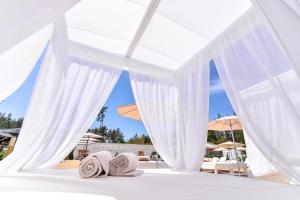 ein weißes Himmelbett mit Kissen und Sonnenschirmen in der Unterkunft Seasons SPA Boutique Hotel in Kozin